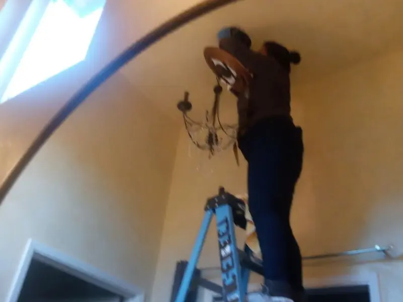 Electrician installing a chandelier in a Wamego residence